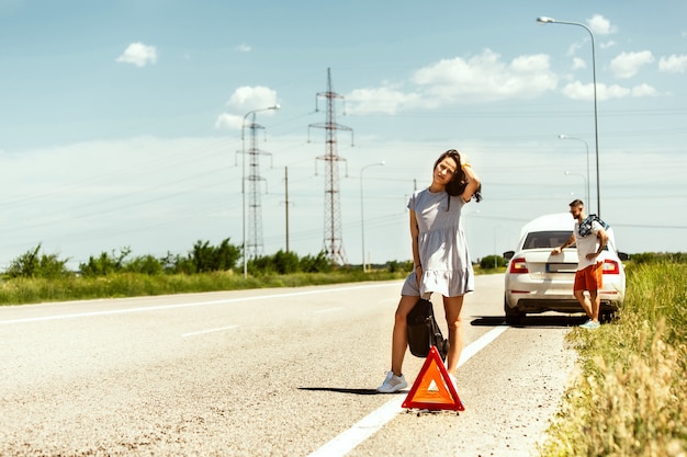 Foto gratuita la joven pareja rompió el auto mientras viajaba camino a descansar.