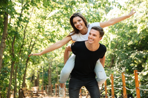 Joven pareja sonriente disfrutando de caballito y riendo