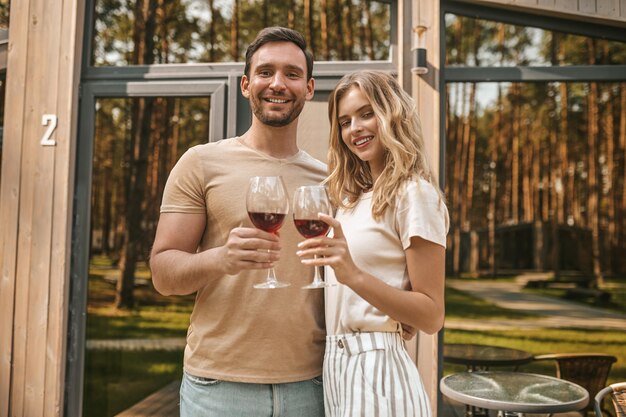 Joven pareja sonriente sosteniendo copas con vino y luciendo feliz