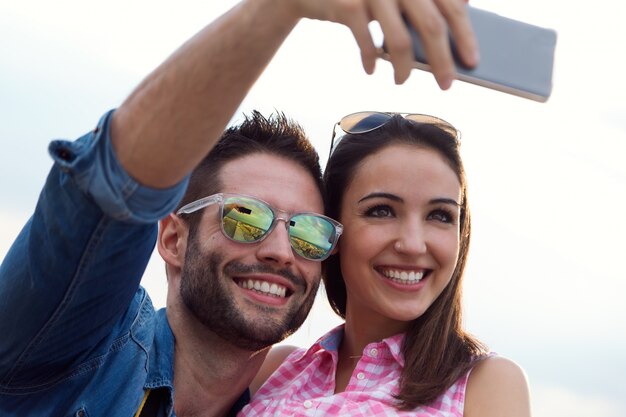 Joven pareja de turistas en la ciudad utilizando el teléfono móvil.