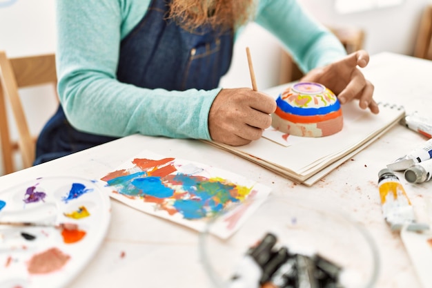 Foto gratuita joven pelirrojo pintando cerámica de arcilla en el estudio de arte