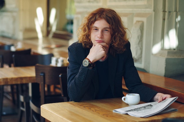 Joven pensando mientras tomando un café