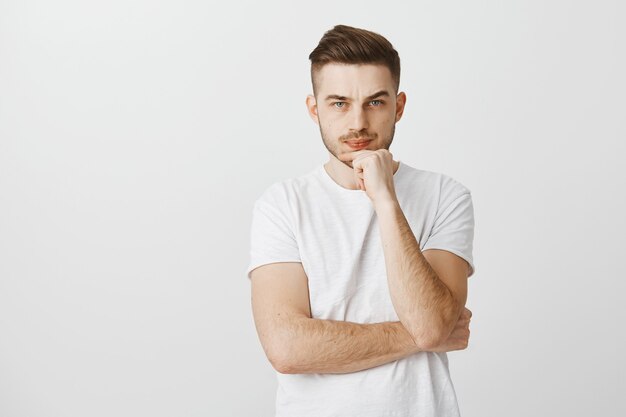 Joven perplejo de aspecto serio tomando una decisión importante