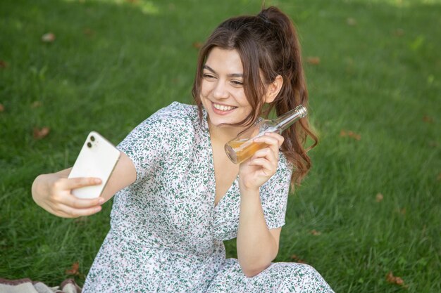 Una joven en un picnic se toma un selfie con una botella de bebida