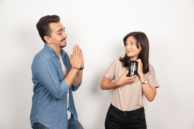 Joven pidiendo una taza de café a una mujer joven.