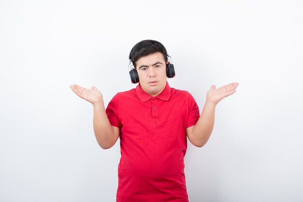 joven de pie y escuchando música con auriculares inalámbricos.