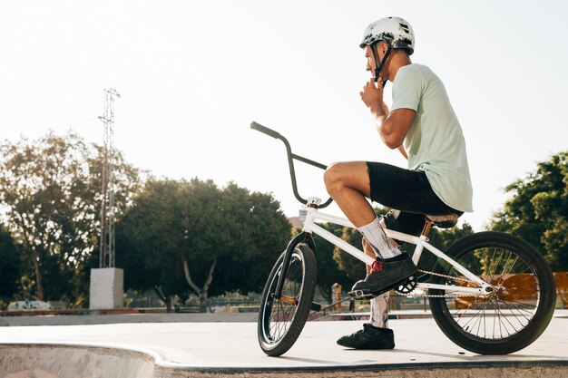 Joven piloto de bmx mirando lejos bajo ángulo de disparo