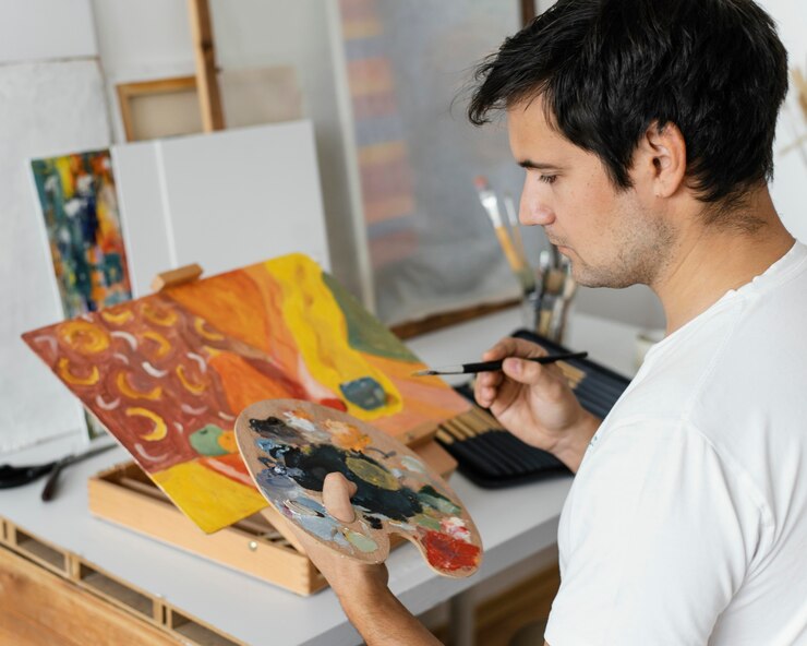 Foto gratuito un joven pintando con acrílicos
