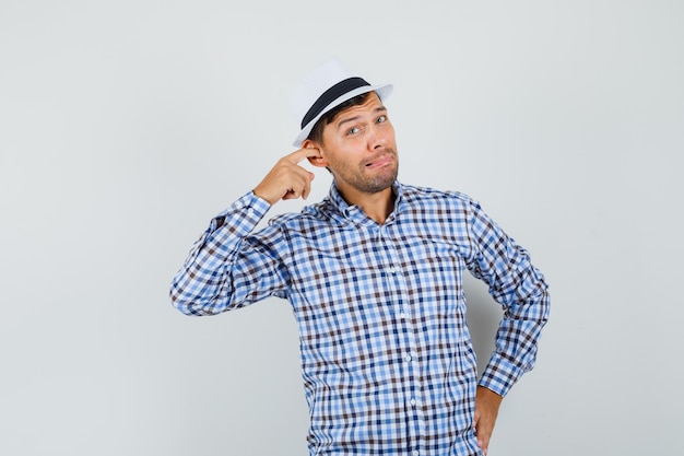 Joven poniendo el dedo en la oreja en camisa a cuadros