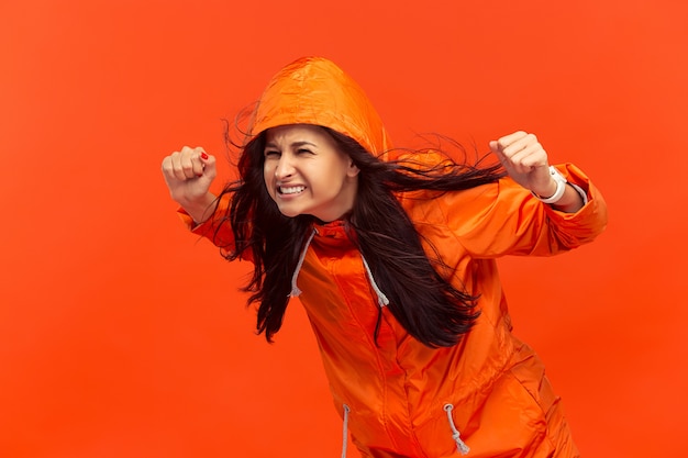 La joven posando en el estudio en chaqueta de otoño aislada en rojo.