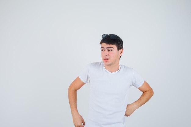 Joven posando mientras mira a un lado en camiseta y se ve bien. vista frontal.