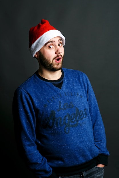 Joven positivo en sombrero rojo de Navidad