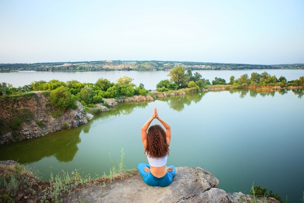 Joven practica yoga cerca del río