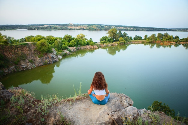 Joven practica yoga cerca del río