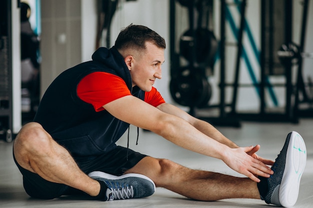 Joven preparador físico que se extiende en el gimnasio