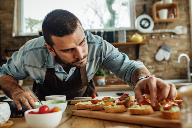 Joven preparando bruschetta con ingredientes saludables en la cocina