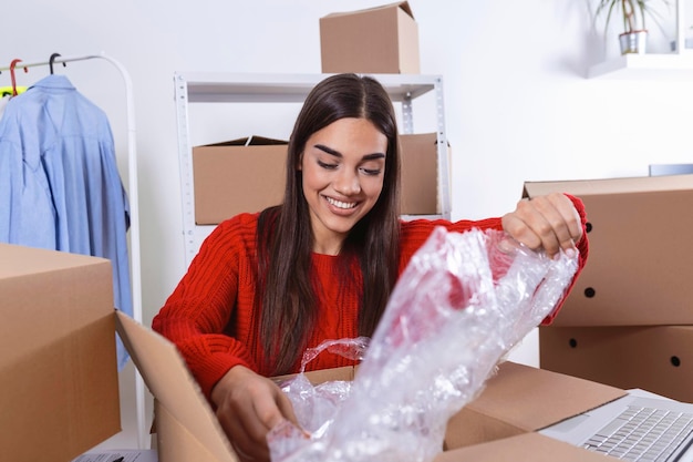 Joven propietaria de una pequeña empresa empacando productos en cajas preparándolos para la entrega Mujeres empacando paquetes con sus productos que vende en línea