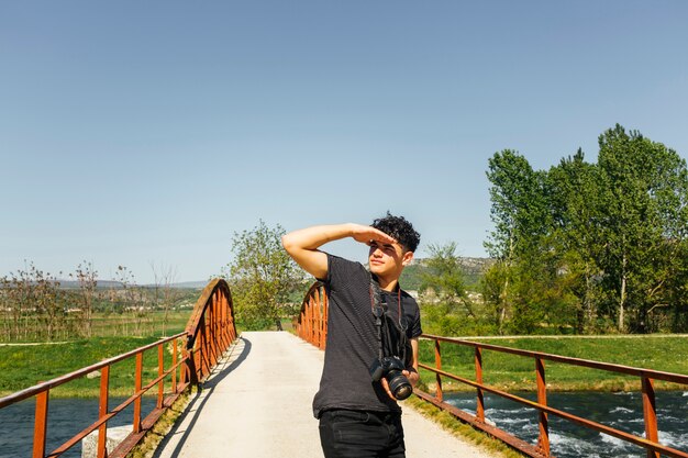 Joven protegiendo el ojo de la luz del sol con cámara de retención