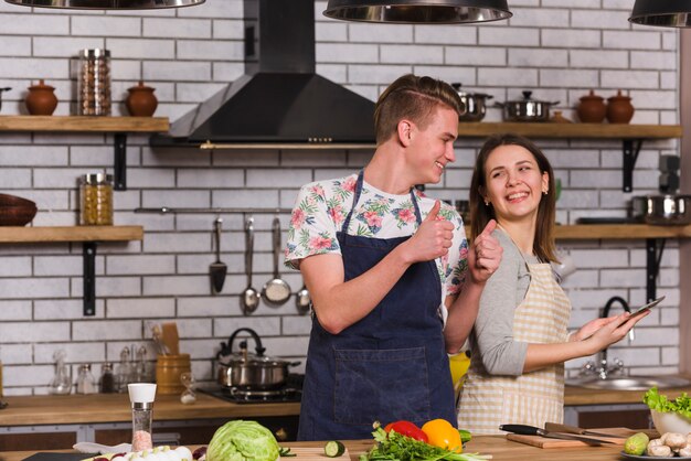 Joven pulgar gesticular a novia mientras cocina juntos