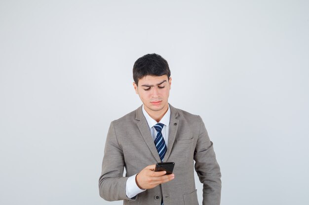 Joven que mira el teléfono en traje formal y que parece centrado. vista frontal.