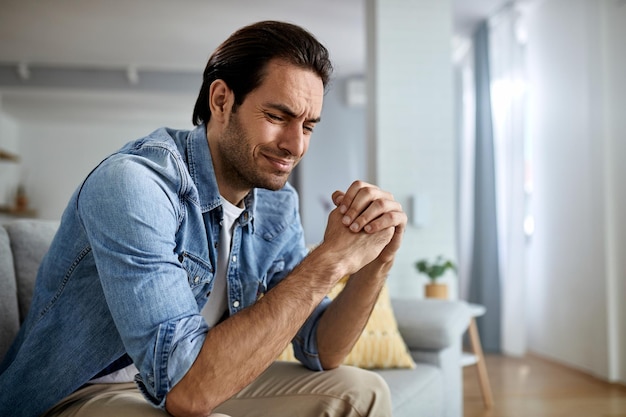 Joven que se siente deprimido mientras está sentado solo en casa