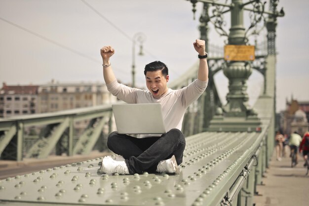 el joven se regocija feliz frente a una computadora