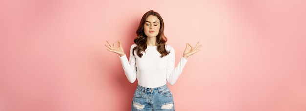 Foto gratuita una joven relajada y atenta meditando, mantén la calma relajándote durante el yoga, cierra los ojos y dobla los dedos