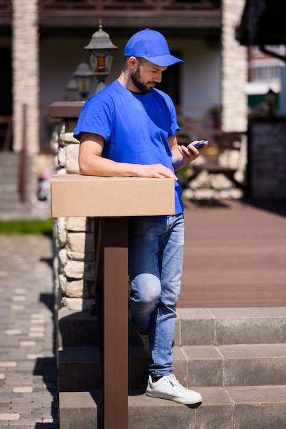 Foto gratuita joven repartidor esperando al cliente al aire libre