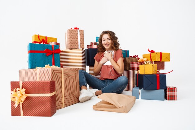 Foto gratuita joven rizada sentada en el piso entre cajas de regalo con tableta actual recién abierta