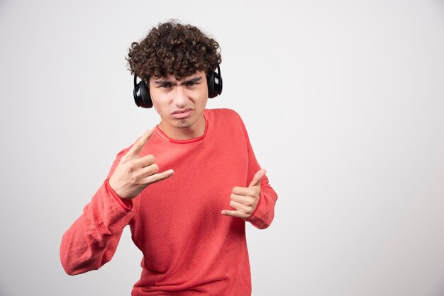 Joven rizado con auriculares haciendo señales.