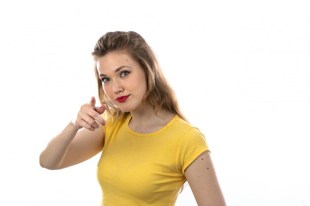 Joven rubia con camiseta amarilla apuntando