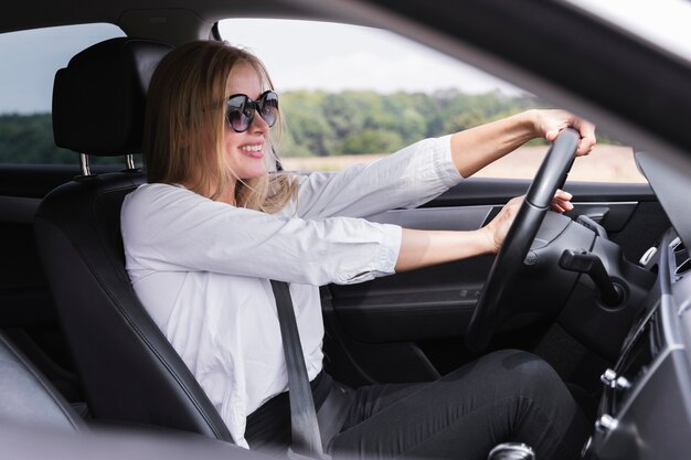 Joven rubia conduciendo un automóvil