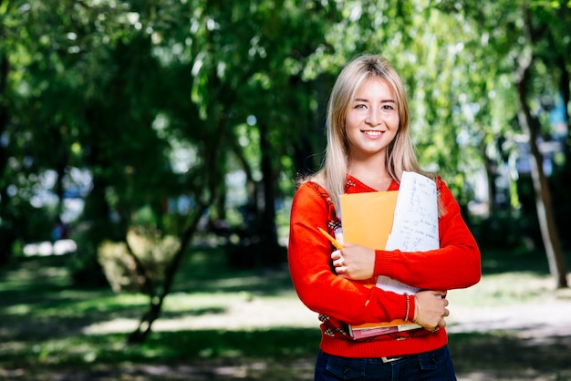 Joven rubia con cuaderno en el jardín