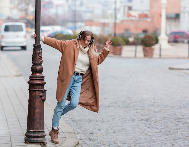 Joven rubia escuchando música con auriculares en la ciudad