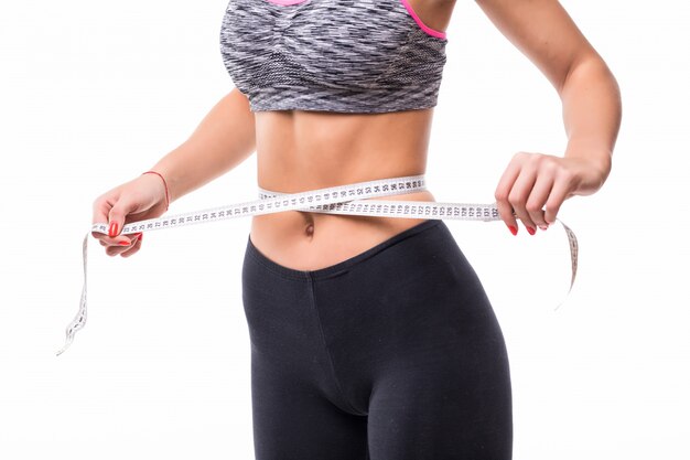 Joven rubia fitness mujer midiendo su cuerpo con regla vestida con ropa deportiva fasion perder peso concepto