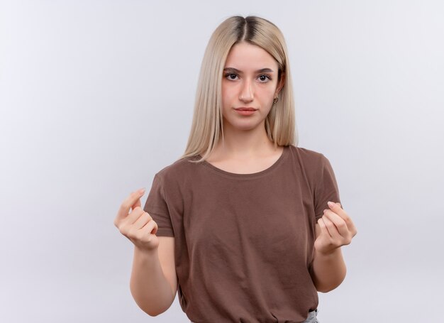 Joven rubia haciendo gesto de dinero en la pared blanca aislada con espacio de copia