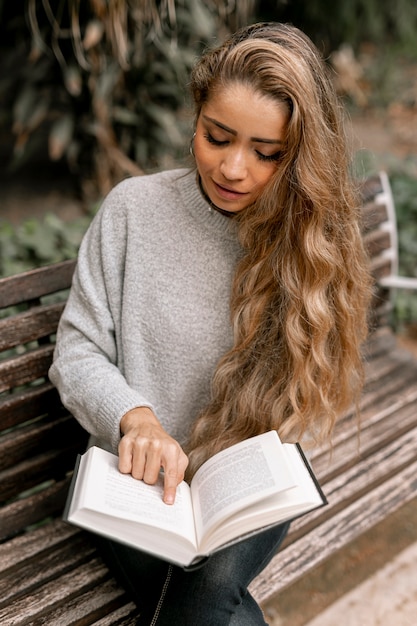 Foto gratuita joven rubia leyendo un libro afuera