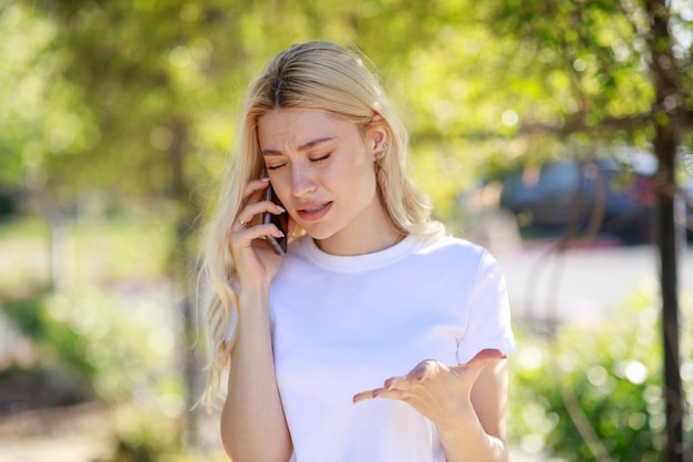 Joven rubia llorando mientras habla por teléfono Foto de alta calidad