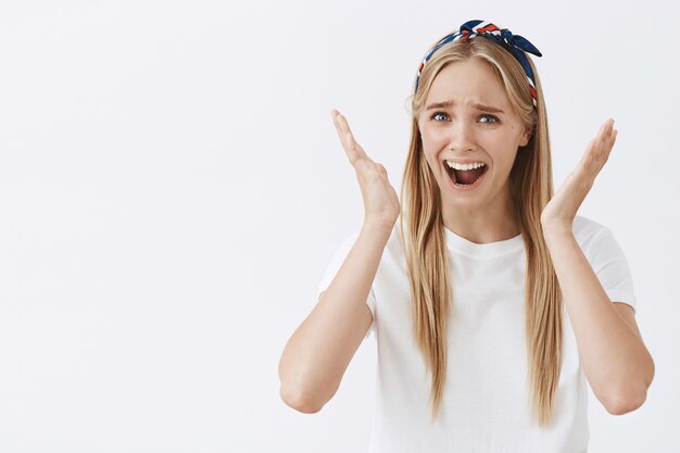 joven rubia posando contra la pared blanca