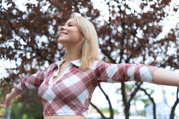 Foto gratuita joven rubia respirando con los ojos cerrados en el parque