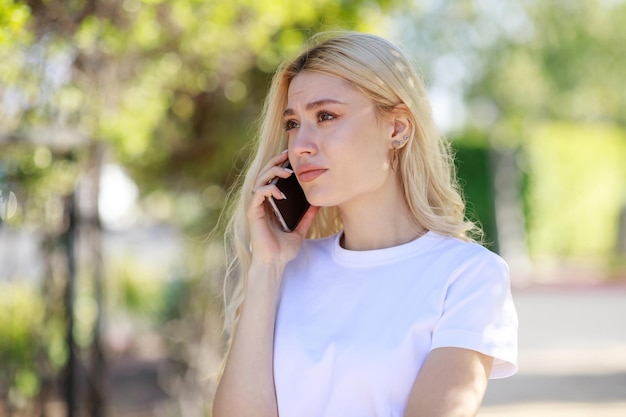 Una joven rubia seria hablando por teléfono y sintiéndose mal