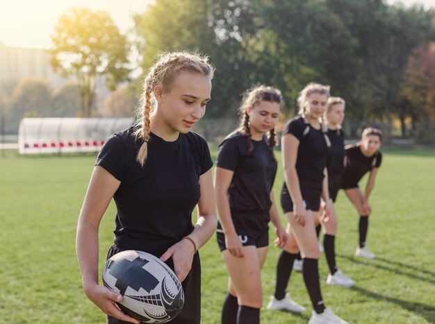 Joven rubia sosteniendo una pelota de rugby