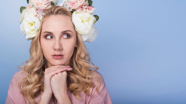 Joven rubia temerosa con guirnalda de flores hermosas