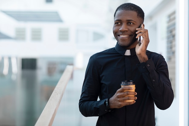 Joven sacerdote masculino hablando por teléfono inteligente