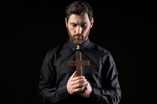 Joven sacerdote rezando con tiro medio cruzado