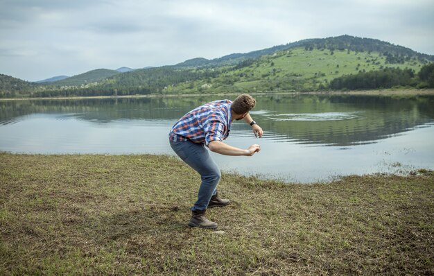 Joven saltando una piedra sobre el agua del lago