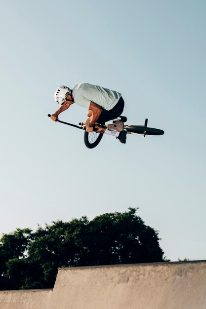 Joven saltando con vista de ángulo bajo de bicicleta bmx