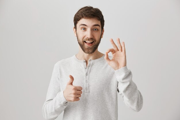 Joven satisfecho muestra el pulgar hacia arriba y el signo bien