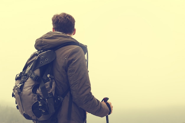 Joven senderismo hombre deportista o viajero con mochila quedarse y mirando en el horizonte. Viraje.