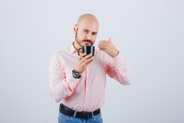 Joven sensación de olor fresco en camisa rosa, jeans, vista frontal.